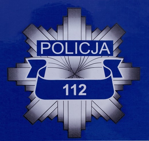 Na grafice znajduje się policyjna gwiazda na granatowym tle, z numerem 112.