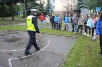 Policjant z Wydziału Ruchu Drogowego tłumaczy zebranym dzieciom ze szkoły Podstawowej w jaki sposób należy pokonywać przeszkody podczas egzaminu kartę rowerową.