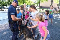 Na zdjęciu widać dzieci głaszczące psa służbowego trzymanego przez policjanta
