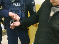 Policjant zdejmuje kajdanki dla zatrzymanego, przed osadzeniem w pomieszczeniu dla osób zatrzymanych.