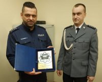 Komendant Komisariatu w Dąbrowie Białostockiej przekazuje kierownikowi pamiątkową tabliczkę.