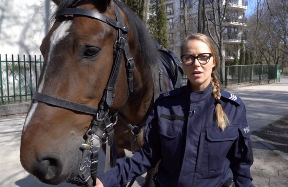Kadr z filmu &quot;Nie bądź jak Katarzyna&quot;, w którym policjantka trzyma konia na wodzy.