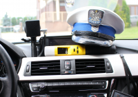 Na masce rozdzielczej radiowozu znajduje się czapka policjanta Wydziału Ruchu Drogowego oraz urządzenie do pomiaru stanu trzeźwości.