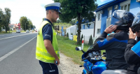 Policjant podczas kontroli drogowej rozmawia z motocyklistami.