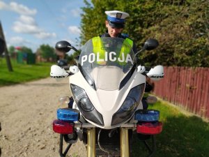 Policjant patrolu motocyklowego wydziału ruchu drogowego wykonuje czynności związane z kontrola drogową.