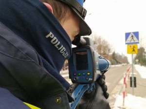 Policjant wydziału ruchu drogowego wykonuje pomiar prędkości ręcznym miernikiem