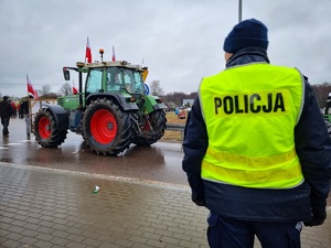Policjant w żółtej kamizelce obok ciągnik rolniczy