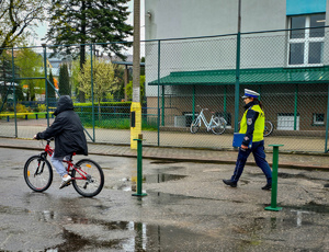 Policjantka sprawdza poprawność wykonania toru jazdy przez dziecko jadące rowerem.