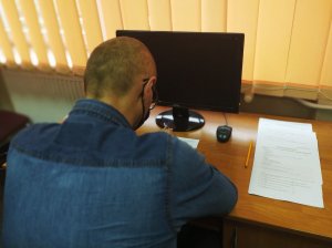 Mężczyzna siedzący przy biurku wypełnia dokumentację