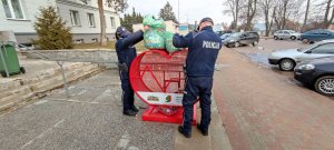 Policjanci z dąbrowskiego komisariatu wsypują nakrętki do czerwonego serca w ramach zbiórki pomocowej.