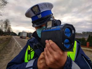 policjant ruchu drogowego kontroluje prędkość za pomocą ręcznego miernika pomiaru prędkości