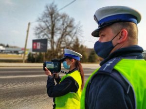 policjant obok policjantka w trakcie pomiaru prędkości pojazdów