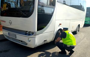 policjant sprawdzający ogumienie autobusu