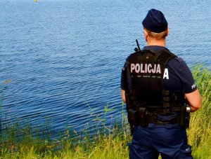 policjant na tle zbiornika wodnego