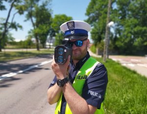 policjant mierzy prędkość w tle droga