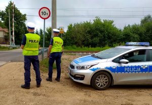 policjanci stojący obok radiowozu w tle przejazd kolejowy
