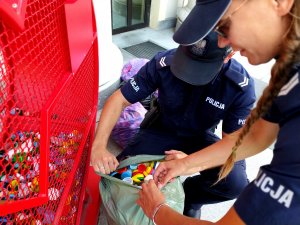 policjantka i policjant otwierają worek z nakrętkami