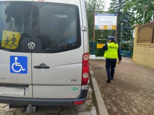 policjantka idąca obok samochodu do przewozu dzieci