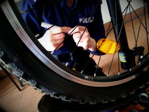 koło roweru za nim policjantka znakująca mazakiem pojazd