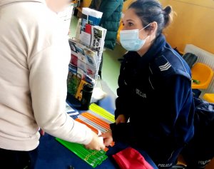 policjantka przed nią ulotki i odblaski kobieta stojąca przed policjantką sięga po ulotki