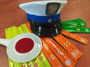 opaski odblaskowe na nich czapka policyjna i znak do zatrzymywania pojazdów