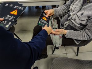 policjantka wręcza starszej kobiecie ulotkę dotycząca oszustw
