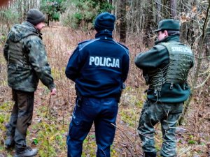 policjant i dwóch strażników leśnych w lesie