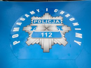 biały napis na niebieskim tle pomagamy i chronimy w środku policja i numer 112