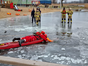 strażak podejmuje osobę z wody przy użyciu sań ratunkowych