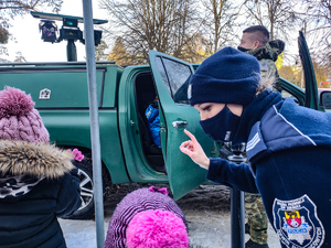 Dzielnicowa wskazuje dziecku pojazd operacyjny straży granicznej