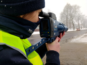 policjantka sprawdza prędkość z jaka jedzie samochód osobowy