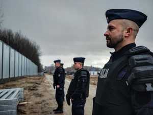 Policjanci stojący na przeciwko budowy zapory granicznej.