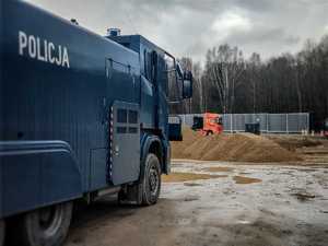 Po lewej stronie pojazd służbowy Tajfun. W oddali budowa zapory granicznej.