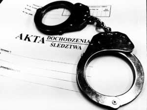 Kajdanki leżące na teczce z napisem akta.