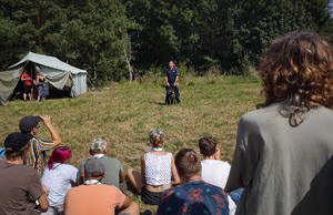 Policjant z psem, przed nim młodzi ludzie.
