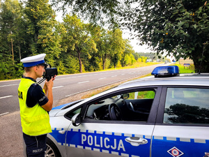 Policjantka mierzy prędkość z jaką jadą samochody.