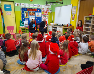 Policjantki w czapkach mikołaja rozmawiają z przedszkolakami.