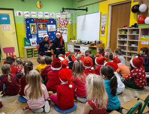 Policjantki w czapkach mikołaja rozmawiają z przedszkolakami.