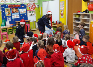 Policjantki w czapkach mikołaja rozmawiają z przedszkolakami.
