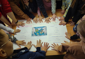 Ręce uczniów i policjantki ułożone na plakacie.