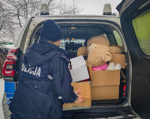 Policjantka wyjmuje karton z radiowozu.