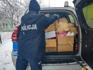 Policjantka wyjmuje karton z radiowozu.