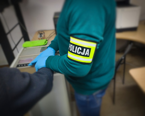 Policjant pobiera odciski palców.