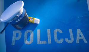 Napis policja na masce radiowozu, czapka policyjna i urządzenie do badania trzeźwości.
