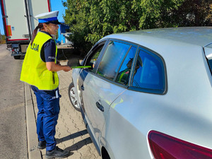 Policjantka wręcza odblask kierowcy samochodu.