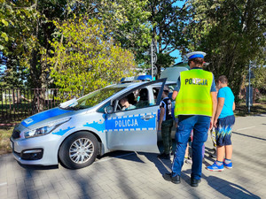 Dzieci w radiowozie, obok policjantka.