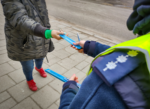 Policjantka wręcza kobiecie odblask.