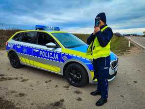 Policjantka mierzy prędkość pojazdów obok radiowóz.