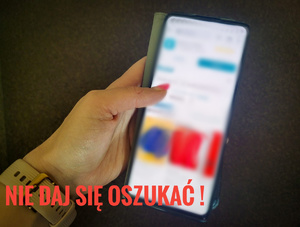 Telefon trzymany w ręku. Obok napis &quot;Nie daj się oszukać!&quot;