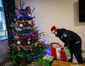 Policjantka układa prezenty pod choinką.
